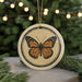 A circular ornament featuring a detailed illustration of a butterfly is displayed against a blurred background of greenery and twinkling lights.