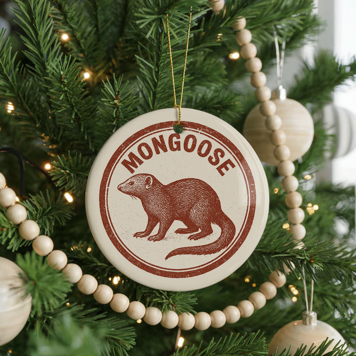 A Christmas tree decorated with ornaments, including a circular ornament with a red and white design featuring a brown moose and the word "MONGOOSE" written on it.