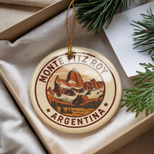 A round ornament with a mountain landscape and the text "MONTE PITZ ROY ARGENTINA" is displayed in a box, surrounded by pine branches.