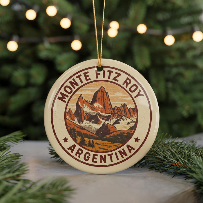 A round ornament with a mountain landscape and text, hanging from a string.