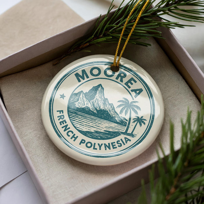 A circular ornament with the text "MOOREA FRENCH POLYNISIA" printed on it, surrounded by pine branches.