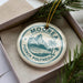 A circular ornament with the text "MOOREA FRENCH POLYNISIA" printed on it, surrounded by pine branches.