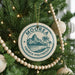 A Christmas tree decorated with ornaments, including a circular ornament with the text "MOORE FRENCH POLYNESIA" and a mountain landscape.