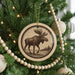 A Christmas tree decorated with ornaments, including a circular ornament featuring a moose illustration.