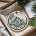 A decorative ornament with the text "Mount Everest Nepal" on it, hanging from a string. The ornament is placed on a surface with pine branches and a white paper.