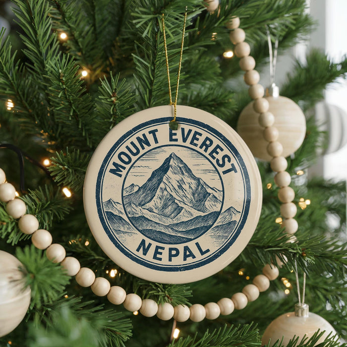 A Christmas tree decorated with ornaments, including a circular ornament with a mountain and Nepal written on it.