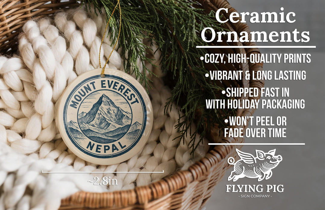 Ceramic ornaments, including a round ornament with a mountain and Nepal printed on it, are displayed in a woven basket.