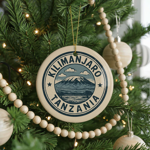 A circular ornament on a Christmas tree, featuring the text "KILIMANJARO TANZANIA" surrounded by a mountain and clouds.