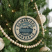 A circular ornament on a Christmas tree, featuring the text "KILIMANJARO TANZANIA" surrounded by a mountain and clouds.