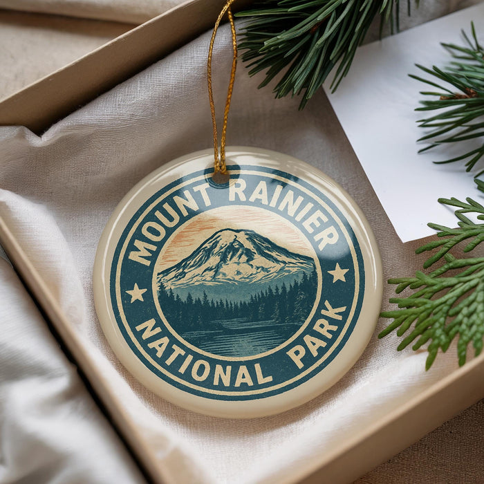A round ornament with the text "MOUNT RAINIER NATIONAL PARK" and a mountain landscape design, hanging from a string.