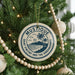 A Christmas tree decorated with ornaments, including a circular ornament with a palm tree design and the text "MUSTIQUE Saint Vincent and the Grenadines".