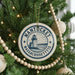 A Christmas tree decorated with ornaments, including a circular ornament with a lighthouse and the text "NANTUCHET MASSACHUSETTS".