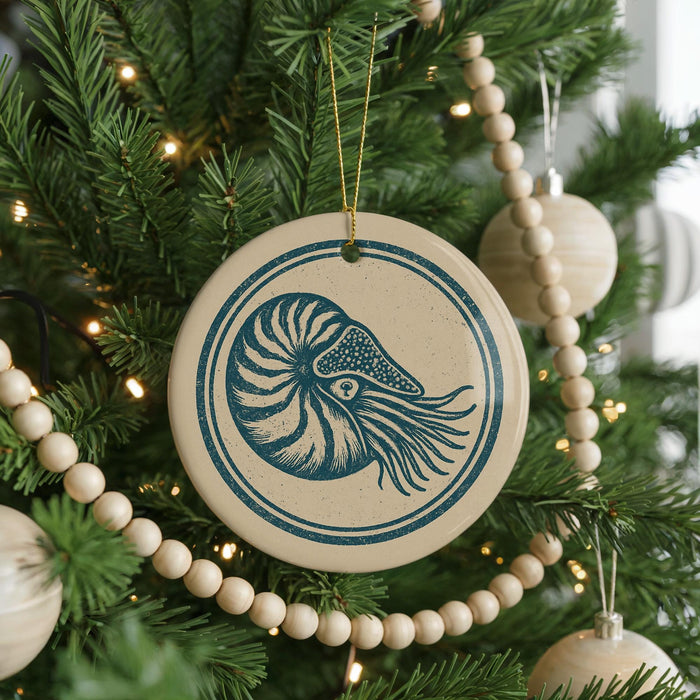 A Christmas tree decorated with ornaments, including a circular ornament with a nautilus shell design.