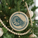 A Christmas tree decorated with ornaments, including a circular ornament with a nautilus shell design.
