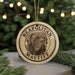 A circular ornament featuring a dog's head and the text "NEAPOLITAN MASTIFF" is displayed in front of a Christmas tree with twinkling lights.