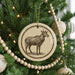 A Christmas tree decorated with ornaments, including a circular ornament featuring a deer silhouette.