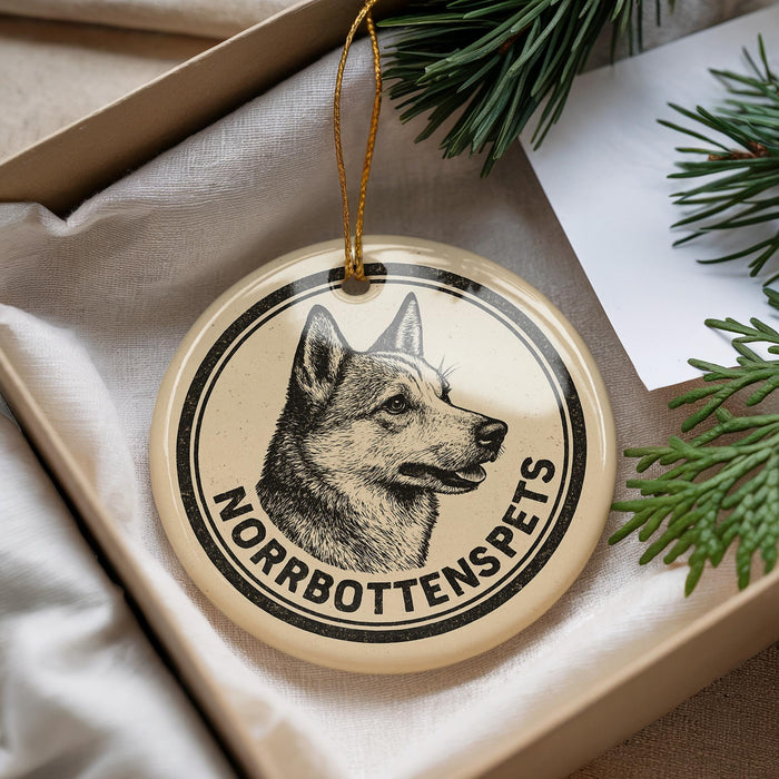 A round ornament with a black and white illustration of a dog's head and the text "NORROBOTTENSPEPS" on it, hanging from a string.