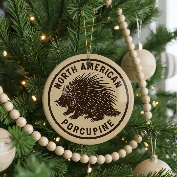 A Christmas tree decorated with ornaments, including a porcupine ornament, and a string of beads.