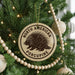A Christmas tree decorated with ornaments, including a porcupine ornament, and a string of beads.