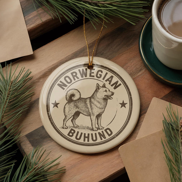 A round ornament featuring a dog, specifically a Norwegian Buhund, is displayed on a wooden surface alongside a cup of coffee and some pine branches.