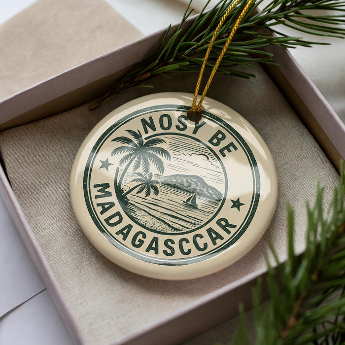 A circular ornament with the text "NOSY BE MADAGASCAR" printed on it, surrounded by a decorative border and a palm tree illustration.