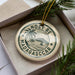 A circular ornament with the text "NOSY BE MADAGASCAR" printed on it, surrounded by a decorative border and a palm tree illustration.