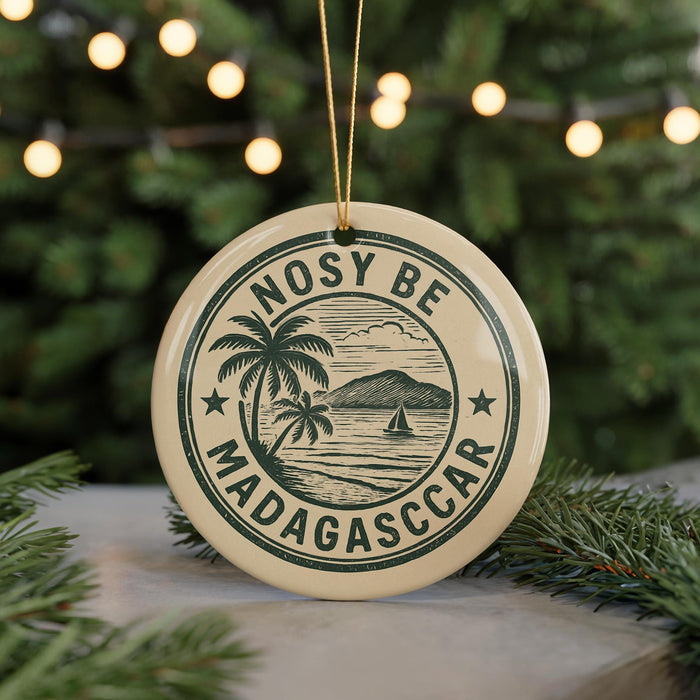 A circular ornament with a palm tree and a sailboat, surrounded by the text "NOSY BE MADAGASCAR".