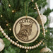 A Christmas tree decorated with ornaments, including a circular ornament with a cat image and the word "OCELOT" written on it.