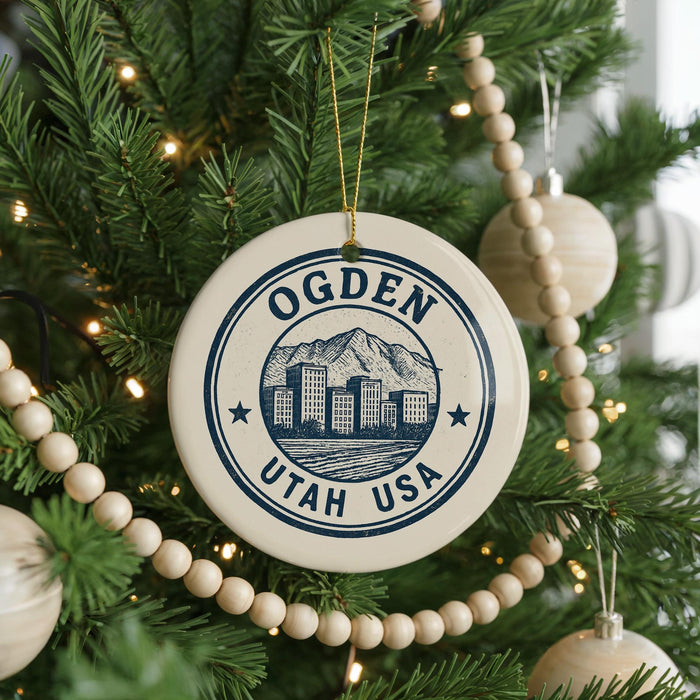 A Christmas tree decorated with ornaments, including a circular ornament with a graphic of a city and mountains, and a beaded ornament.