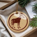 A circular ornament featuring a zebra illustration is displayed in a box, surrounded by pine branches.