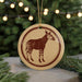 A circular ornament featuring a zebra silhouette is displayed against a blurred background of a Christmas tree with twinkling lights.