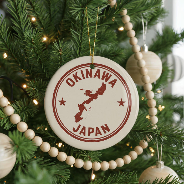 A Christmas tree decorated with ornaments, including a circular ornament with the text "OKINAWA JAPAN" and a map of Japan.