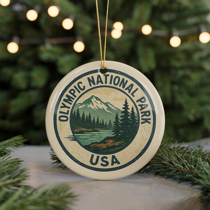 A circular ornament with the text "OLYMPIC NATIONAL PARK USA" and a mountain landscape design, hanging from a string.