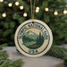 A circular ornament with the text "OLYMPIC NATIONAL PARK USA" and a mountain landscape design, hanging from a string.
