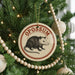 A Christmas tree decorated with ornaments, including a circular ornament with a picture of an opossum and the word "OPOSSIUM" written on it.
