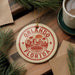 A circular ornament with the text "ORLANDO FLORIDA" printed on it, surrounded by pine branches and a cup of coffee on a wooden surface.