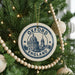 A Christmas tree decorated with ornaments, including a circular ornament with the text "Oxford, England" and a picture of a building.