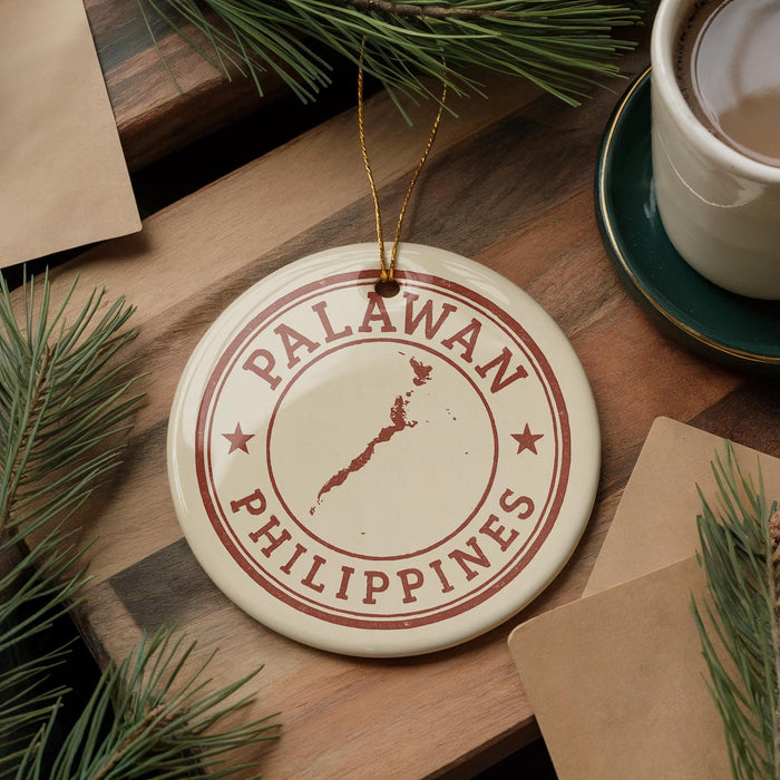 A circular ornament with the text "PALAWAN PHILIPPINES" and a map of the Philippines, placed on a wooden surface next to a cup of coffee and some pine branches.