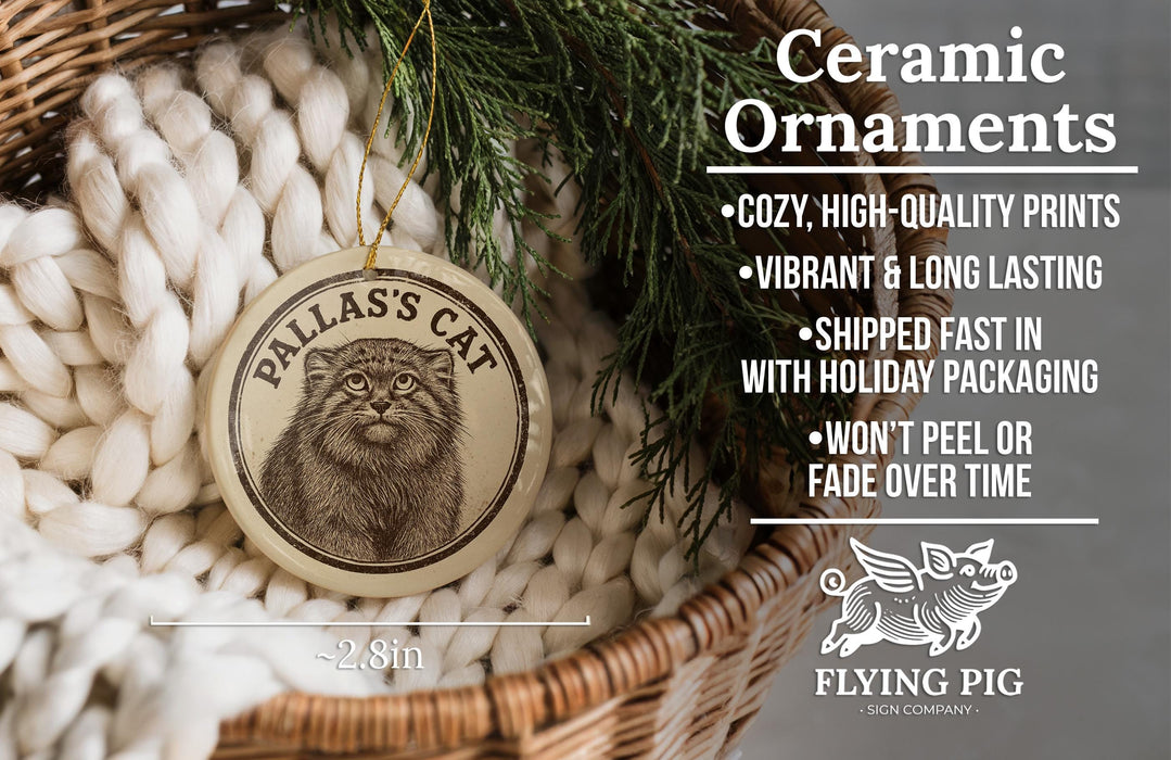 Ceramic ornaments, featuring a cat image, are displayed in a basket with a pine branch.