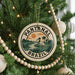 A circular ornament on a Christmas tree, featuring a bird and palm trees, with the text "PANTANAL BRASIL" around the edge.