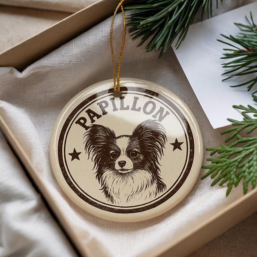 A circular ornament with a Papillon dog's face and the word "Papillon" printed on it, hanging from a string.