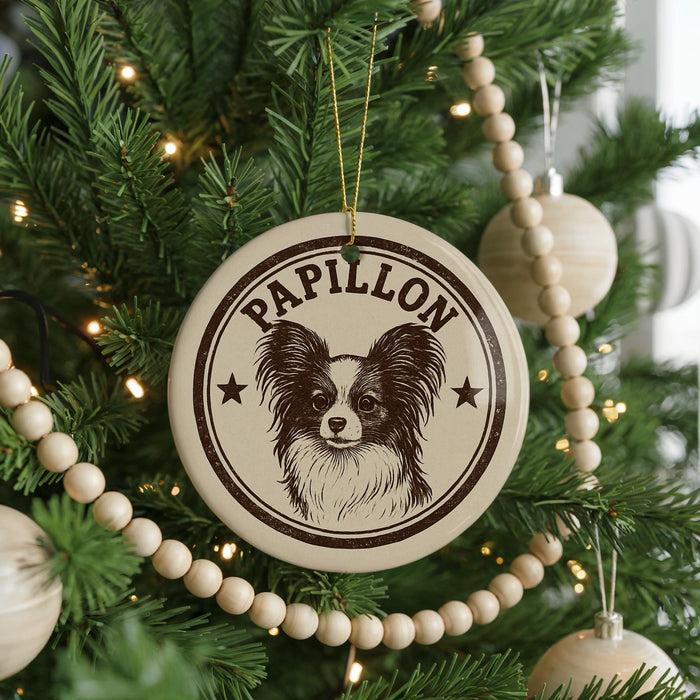 A Christmas tree decorated with ornaments, including a circular ornament with a Papillon dog image and the word "Papillon" written on it.
