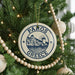 A circular ornament on a Christmas tree, featuring a design of a Greek island and the text "PAROS GRECE".