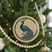 A Christmas tree decorated with ornaments, including a circular ornament featuring a peacock design.