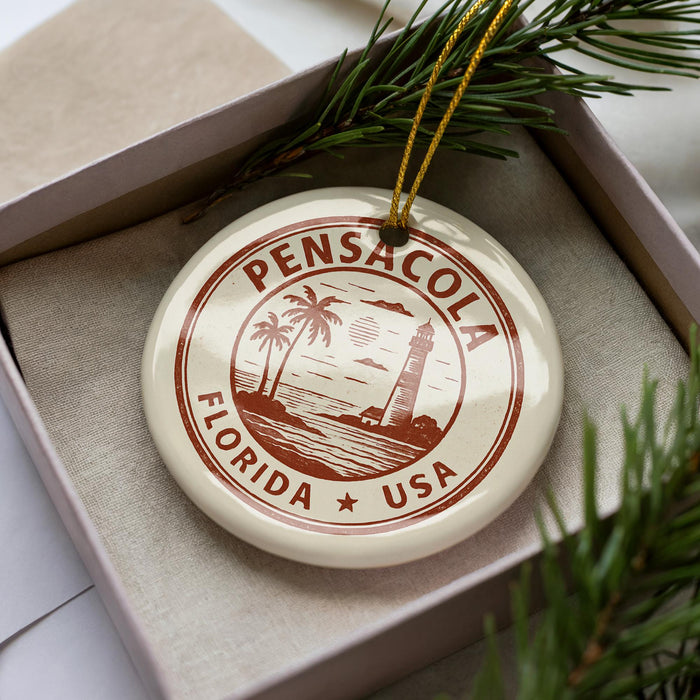 A round ornament with the text "PENSACOLA FLORIDA USA" printed on it, surrounded by pine branches.