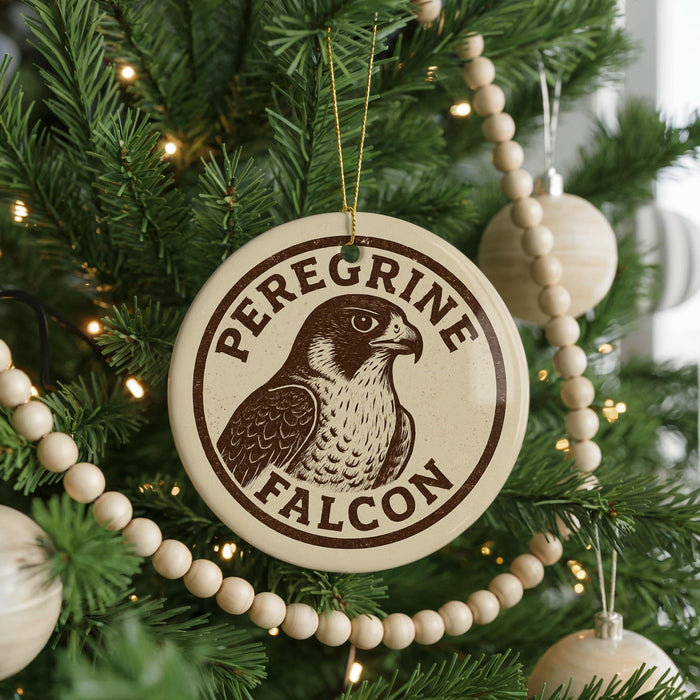 A Christmas tree decorated with ornaments, including a round ornament with a bird image and the text "Peregrine Falcon" around it.