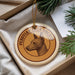 A round ornament with a dog's head on it, hanging from a string.