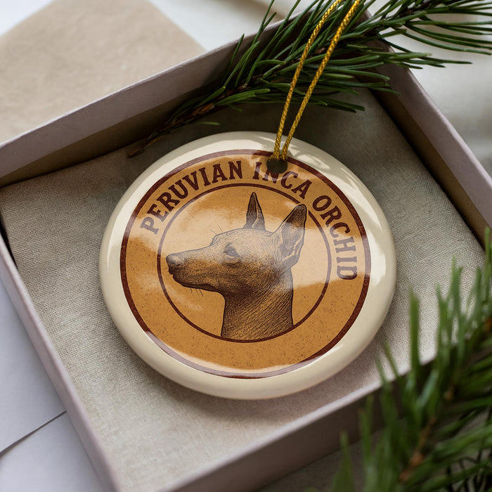 A round ornament with a dog's head on it, placed inside a box with pine branches.