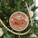 A Christmas tree decorated with ornaments, including a circular ornament with a red and white design that says "PetriFied Forest National Park USA".