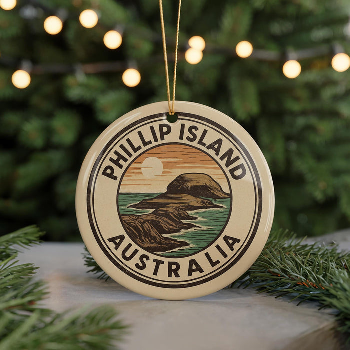 A round ornament with the text "PHILLIP ISLAND AUSTRALIA" and an illustration of a mountain and ocean, hanging from a string.